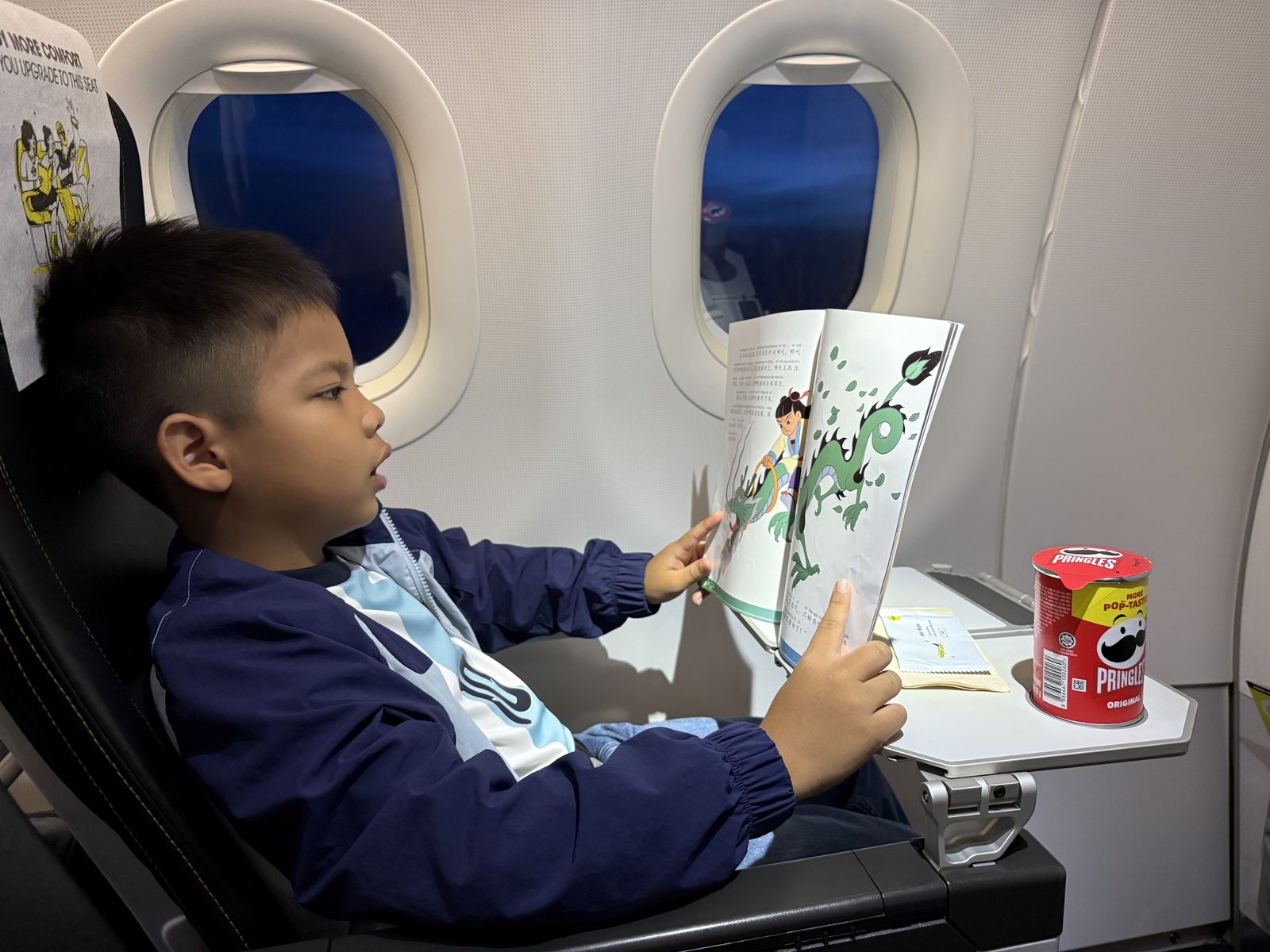 Seven-and-a-half-year-old boy reading a 47-page Chinese Nezha storybook by himself on a flight to China